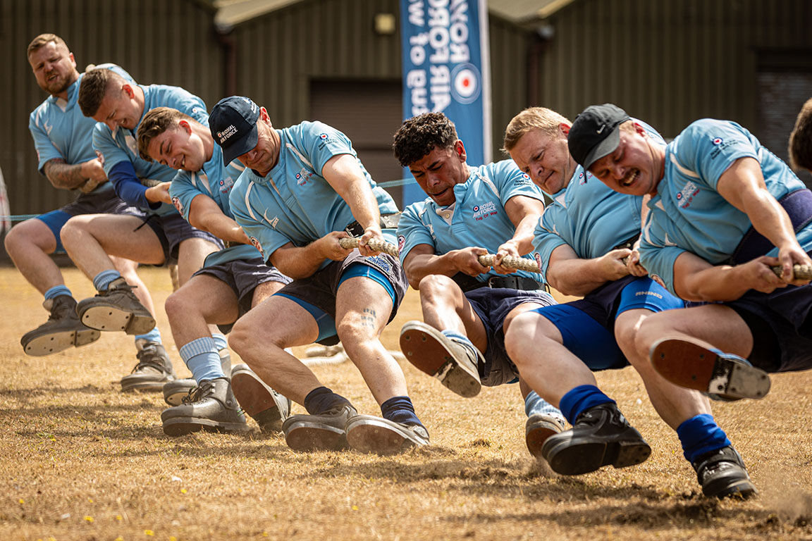 Image shows RAF aviators pulling on a rope during tug of war game on the sand. 